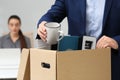 Dismissed man packing personal stuff into box in office, closeup Royalty Free Stock Photo