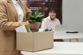 Dismissed woman packing personal stuff into box in office, closeup Royalty Free Stock Photo
