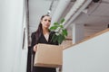 Dismissed woman walking with personal stuff into box in office Royalty Free Stock Photo