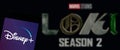Disney Plus logo on smartphone screen with defocused logo of Marvel StudiosÃ¢â¬â¢ Loki Season 2 on screen in the background
