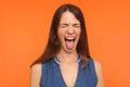 Disobedient crazy brunette woman in denim clothes sticking out tongue and grimacing with closed eyes Royalty Free Stock Photo