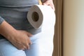 Disorder, Diarrhea, incontinence. Healthcare concept. Woman hand holding her crotch lower abdomen and tissue or toilet paper roll Royalty Free Stock Photo