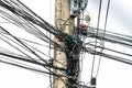 Disorder messy line of black electrical wires on old power pole. Complicated arrangement of electrical cables with a sky