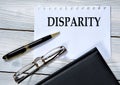 DISPARITY - word in white paper on the background of a diary, glasses and pen Royalty Free Stock Photo