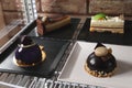 Display case with different delicious desserts on shelf in cafe, closeup