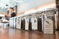 Varieties of specialty coffee beans from many countries in glass mason jars display for clients on the wooden counter at the coffe