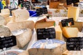 A display of tasty looking cheeses for sale a local farmers market, the cheese in the foreground are oput of focus to provide