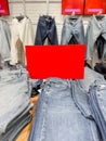 A display of various jeans in a retail store. The foreground features folded blue jeans, while the background shows hanging denim Royalty Free Stock Photo