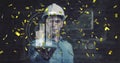 Displaying holographic skyscrapers, helmeted engineer using interface in studio, with confetti Royalty Free Stock Photo