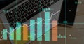 Displaying multicolored financial data visualization over work desk, with laptop and smartphone Royalty Free Stock Photo