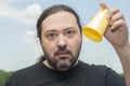 Displeased adult man with a beard upset shows an empty, yellow plastic cup Royalty Free Stock Photo