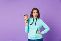 Displeased beautiful young woman posing over purple background wall drinking coffee