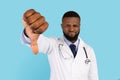 Displeased Black Male Doctor Showing Thumb Down Gesture At Camera