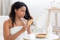 Displeased Black Woman Combing Her Tangled Hair With Bamboo Brush