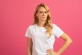 Displeased blonde lady expresses disapproval and frowning on pink background Royalty Free Stock Photo