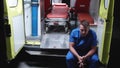 Sad corpsman sit in ambulance car at night.