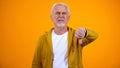 Displeased elderly man showing thumbs-down gesture, dislike, negative feedback Royalty Free Stock Photo