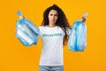 Displeased Female Volunteer Holding Plastic Garbage Bags On Yellow Background