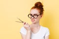 Displeased ginger woman in eyeglasses looking on dividers