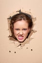 Displeased girl peeping through hole in paper Royalty Free Stock Photo