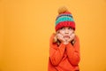 Displeased girl in sweater and hat reclines on her arms