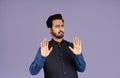 Displeased Indian guy making denial gesture over violet background