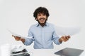 Displeased indian man is holding papers and sitting by table Royalty Free Stock Photo