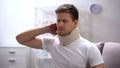 Displeased man in foam cervical collar suddenly feeling pain in neck, trauma Royalty Free Stock Photo