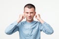 Displeased man plugging ears with fingers. He does not want to listen to arguments