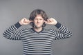 Displeased man plugging ears with fingers doesn`t want to listen anything isolated on gray wall background. Young Royalty Free Stock Photo