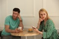 Displeased man and woman with smartphones in cafe. Failed first date