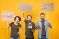 Displeased protesting young people hold protest signs broadsheet placard scream in megaphone isolated on yellow