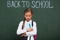 Displeased schoolgirl holding pen and book