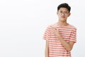 Displeased smart young attractive asian male student in glasses and t-shirt raising eyebrow in scorn and doubt pursing Royalty Free Stock Photo