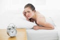 Displeased woman in bed with alarm clock in foreground Royalty Free Stock Photo