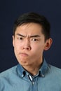 Displeased young Asian man making face