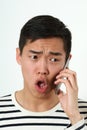 Displeased young Asian man using a smartphone