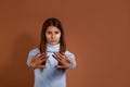 Displeased young european woman wearing light blue sweater shows stop sign prohibition symbol, keeps both palms forward to camera