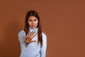 Displeased young european woman wearing light blue sweater shows stop sign prohibition symbol, keeps palm forward to camera,