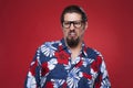 Displeased young man in Hawaiian shirt against red background