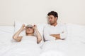 Displeased young man looking at woman wearing eye mask in bed