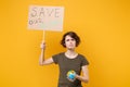 Displeased young protesting girl hold protest sign broadsheet placard on stick Earth world globe isolated on yellow