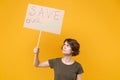 Displeased young protesting girl hold protest sign broadsheet placard on stick isolated on yellow background studio