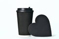 A disposable black paper cup for coffee and a heart-shaped sign. Paper cups for hot coffee. Coffee to go. Paper cup for Royalty Free Stock Photo