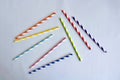 Disposable colorful striped paper cocktail sticks lie chaotically on light blue background. Eco friendly paper drinking straws. Royalty Free Stock Photo
