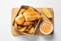 Disposable container with British Traditional Fish and potato chips on wooden background Royalty Free Stock Photo