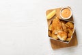 Disposable container with British Traditional Fish and potato chips on wooden background, top view. Royalty Free Stock Photo