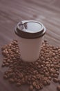 Disposable cup of coffee and coffee beans over dark wood background with space for your text Royalty Free Stock Photo