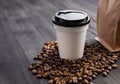 Disposable cup of coffee and coffee beans over dark wood background with space for your text Royalty Free Stock Photo