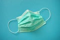 Disposable face mask. Green blue medical respirator breathing face dust mask on blue background. Coronavirus Covid-19 prevention. Royalty Free Stock Photo